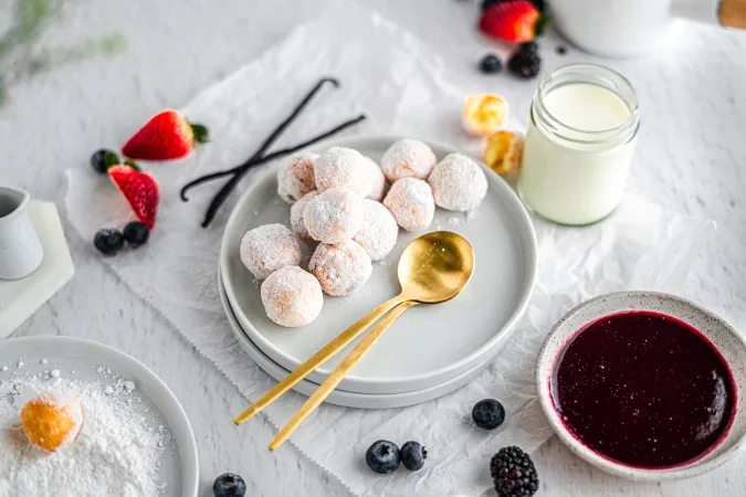 donuts stacked in a pyramid on a white plate with assorted berries and dipping sauce