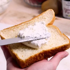 Butter knife spreading whipped cream on brioche bread