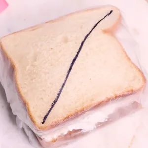 whipped cream fruit sandwich covered in plastic wrap with a sharpie line showing diagonal cut on sandwich