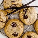 Carmel brown colored chocolate chip cookies on cooling rack with vanilla beans and vanilla extract