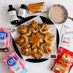 top view of the star bread with Rodelle, Danish Creamery, Platinum Yeast, C&H sugar, and sun-maid california figs products surrounding the bread.