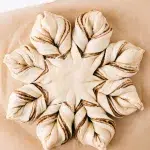 Close up top shot of the star bread with layers of fig jam between that's ready to bake. It lays on brown parchment paper.