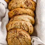 Top shot of a group of Halva cookies laying in a straight line in a bread tin with a light tan towel, holding the cookies.