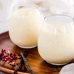 Vanilla mango smoothie in short cups on wooden background