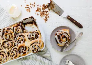 Inside out sticky pecan buns in tray and on plate with scattered pecan pieces 