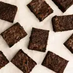 top view of gluten free brownies cut into squares on white parchment paper.