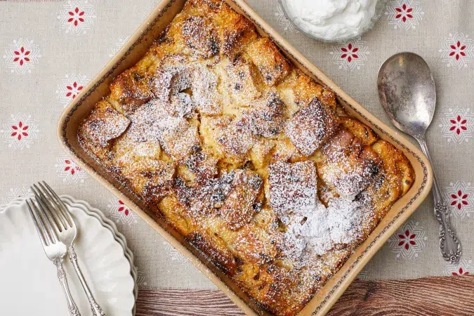 Finished panettone bread pudding on table with forks, plate and serving spoon